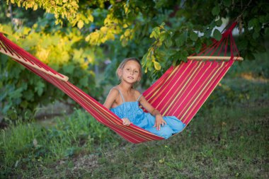 Güzel bir kız hamakta dinleniyor. Kız telefonda selfie çekiyor. Aile memnuniyeti. Bir yaz günü dinlenin. gülümseyen çocuk.