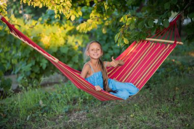 Güzel bir kız hamakta dinleniyor. Kız telefonda selfie çekiyor. Aile memnuniyeti. Bir yaz günü dinlenin. gülümseyen çocuk.