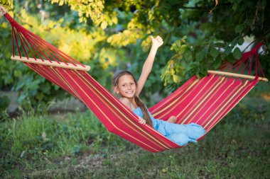 Güzel bir kız hamakta dinleniyor. Kız telefonda selfie çekiyor. Aile memnuniyeti. Bir yaz günü dinlenin. gülümseyen çocuk.