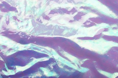 Holografik parlak gökkuşağı çok renkli gerçek buruşuk doku arkaplanı açık mavi - mor tonlu.