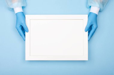 Hastalığın koronavirüse karşı temasının gerçek fotoğrafı. Tıbbi eldivenli eller mavi arkaplanda yazılar olan bir poster tutuyor..