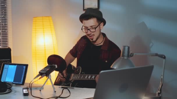 Evde kayıt stüdyosu: Gitar çalan ve hit şarkısını söyleyen neşeli müzisyen — Stok video