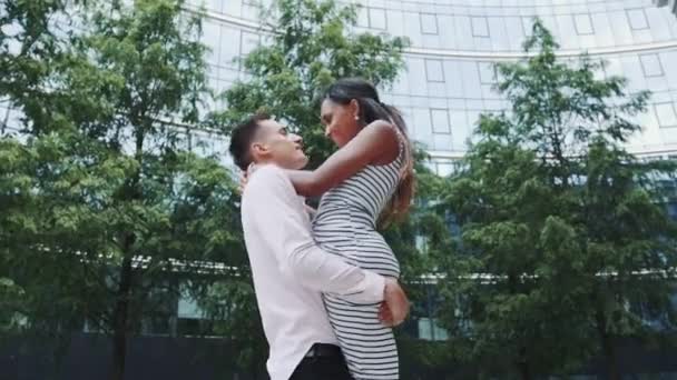 Handsome boy spinning around and kissing his mixed-race girlfriend outdoors — Stock Video