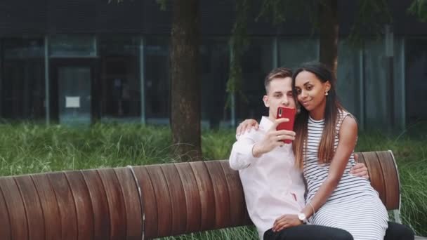 Zoom colpo di bella coppia mista fare selfie all'aperto — Video Stock