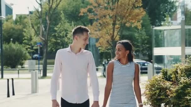 Multi-etnikai pár félénken néz egymásra, miközben sétálnak az utcán — Stock videók