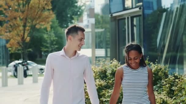 Семья из двух смешанных рас, держащихся за руки, ходящих и разговаривающих друг с другом — стоковое видео