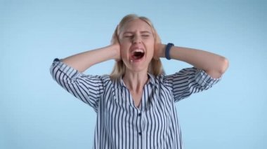 Korkak çaresiz kadın çığlık atıyor ve mavi arka planda kulakları örtüyor.