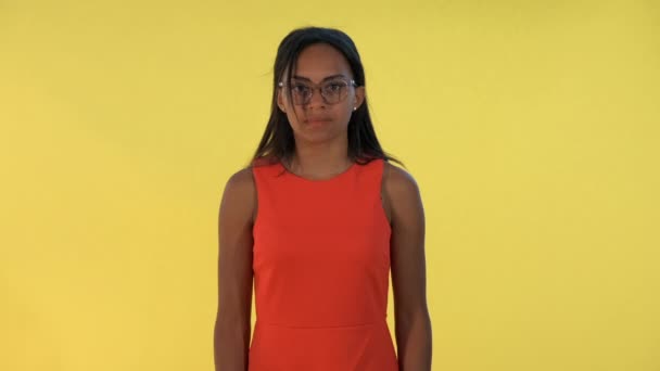 Blandad ras ung kvinna sprider sina händer till sidorna och säger "vad" på gul bakgrund — Stockvideo