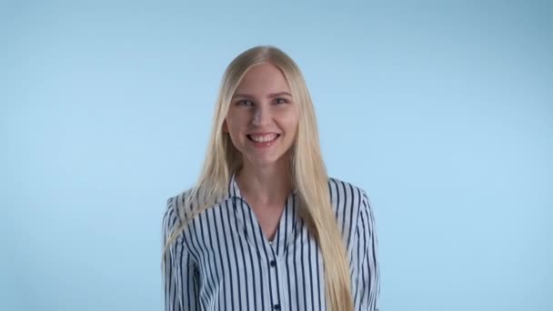 Mujer rubia emocionada gritando y levantando puños en alegría sobre fondo azul . — Vídeo de stock