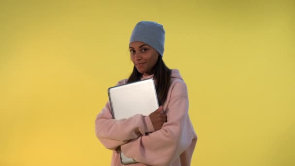 Portrait of African girl in cap hugging her computer laptop — Stock Video