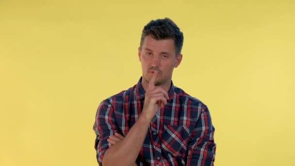 Detailní záběr mladého muže dělat tiché gesto na žlutém pozadí. — Stock video