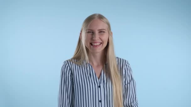 Happy young lady bursting in laughter on blue background — ストック動画