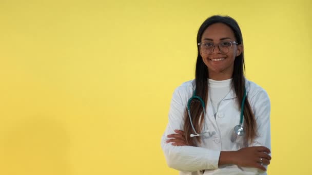 Porträt einer afrikanischen Ärztin, die auf gelbem Hintergrund in die Kamera lächelt. — Stockvideo