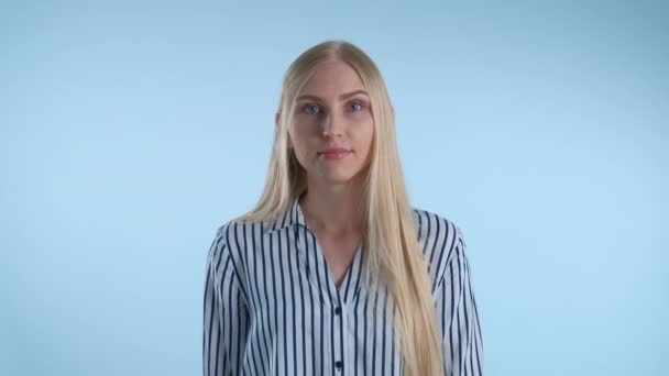 Blonde young woman misunderstanding something on blue background. — Stock Video