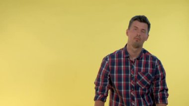 Kareli gömlekli sıkıcı bir adam parmak tabancasıyla kendini başından vuruyor ve sonra da yere düşüyor..