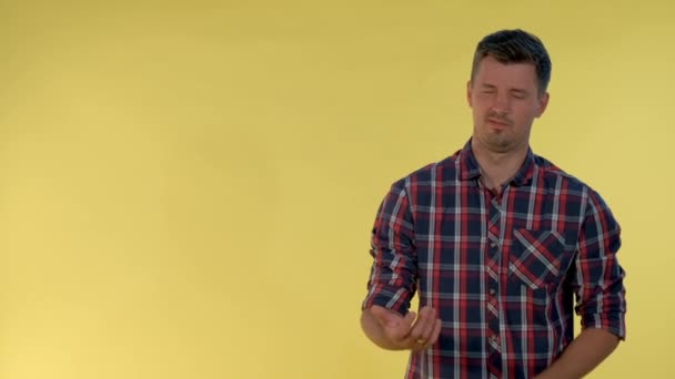 Portrait of dark-haired man in checkered shirt showing negative feelings and giving thumbs down. — Stock Video