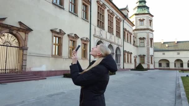 Девушка-туристка делает фотографии дворца в старом городе. — стоковое видео