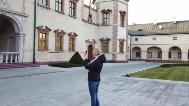 Девушка-туристка делает фотографию дворца на старой площади — стоковое видео