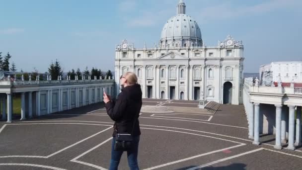 Dziewczyna robi zdjęcie spacerując pieszo w pobliżu miniaturowego modelu Bazyliki św. Piotra w Watykanie. Park Miniatur. — Wideo stockowe