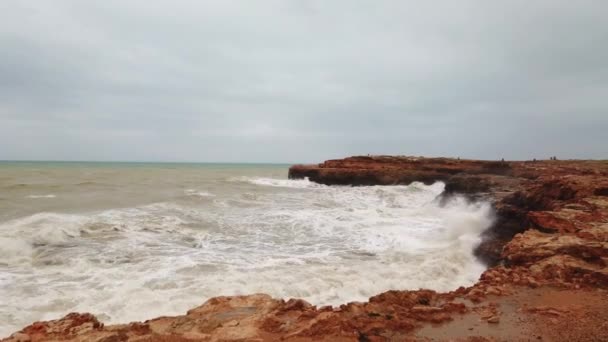 石に打ち寄せる波から水が飛び散る嵐の海空の下の岩に打ち寄せる波｜4K — ストック動画