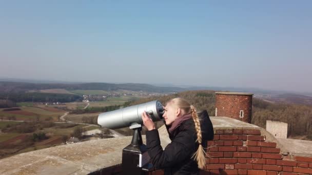 Atractivo viajero femenino utilizando el visor óptico de la torre para mirar alrededor del valle cerca del antiguo castillo — Vídeos de Stock