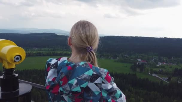 Mujer mira una hermosa vista en la cima de una montaña . — Vídeos de Stock
