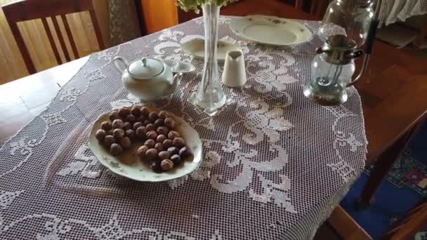 Plate with nuts, old kettle and a vase with flowers. Old Celtic village. — Stock Video