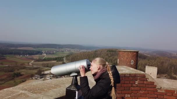Atractivo viajero femenino usando prismáticos para mirar alrededor del valle cerca del antiguo castillo — Vídeos de Stock