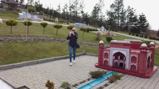 Женщина делает фото, гуляя пешком возле миниатюрного макета здания Тадж-Махал. Парк миниатюр. — стоковое видео