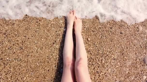 L'acqua di mare lava gambe femminili su una spiaggia — Video Stock