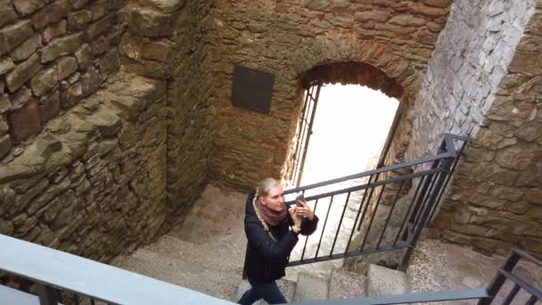 Une fille marche à travers un vieux château et prend des photos — Video