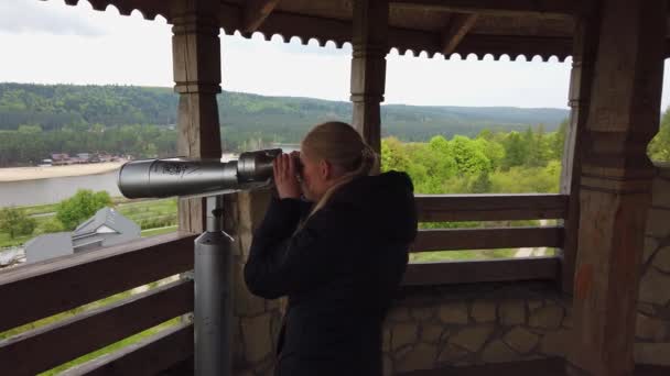 Приваблива жінка мандрівник використовує Tower Optical переглядач для пошуку навколо долини біля старого замку — стокове відео