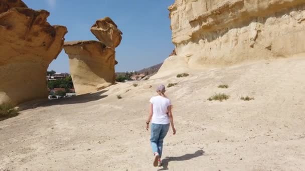 Κορίτσι που περπατά στην έρημο κοντά σε κίτρινο φουτουριστικό βράχο. — Αρχείο Βίντεο