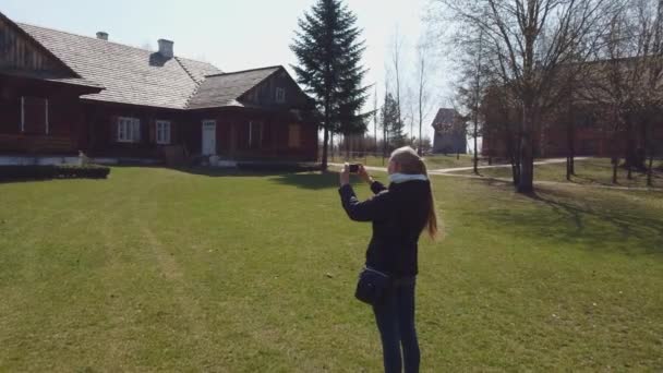 Mulher turista faz uma fotos de casa de madeira em uma antiga aldeia europeia — Vídeo de Stock