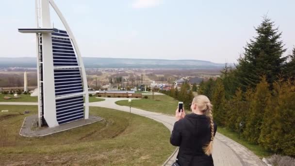 Жінка фотографує ходьбу пішки біля мініатюрної моделі Бурдж Аль-Араб Джумейра. Парк мініатюр. — стокове відео