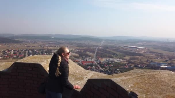 Attractive female traveller looking around valley near the old castle — Stock Video