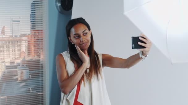 En sesión de fotos romper hermoso modelo africano haciendo selfie en el teléfono inteligente en el estudio profesional — Vídeos de Stock