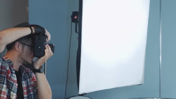 Профиль кавказского фотографа, работающего в студии с мягкой коробкой на заднем плане — стоковое видео