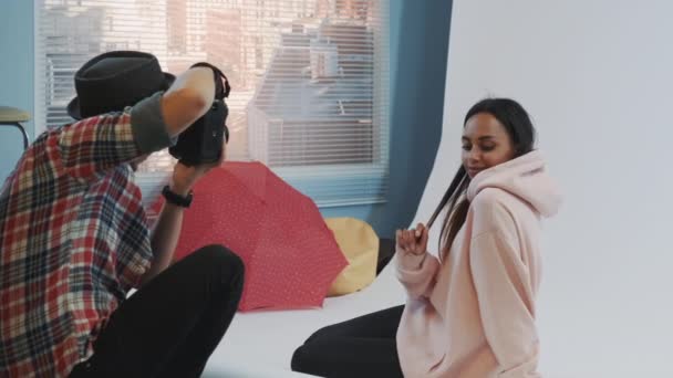 Primo piano di make-up artist applicare il trucco sul bellissimo modello nero seduto sul pavimento e in posa — Video Stock