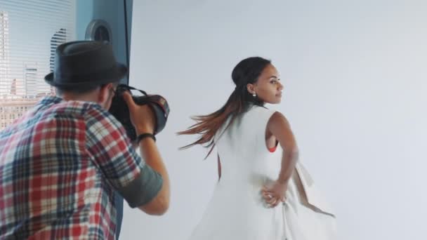 Vista trasera del fotógrafo tomando fotos de un hermoso modelo multirracial en el estudio — Vídeos de Stock