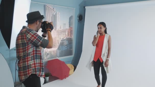 Scena za kulisami sesji zdjęciowej: wielorasowa młoda kobieta pozująca do sesji zdjęciowej magazynu o modzie. — Wideo stockowe