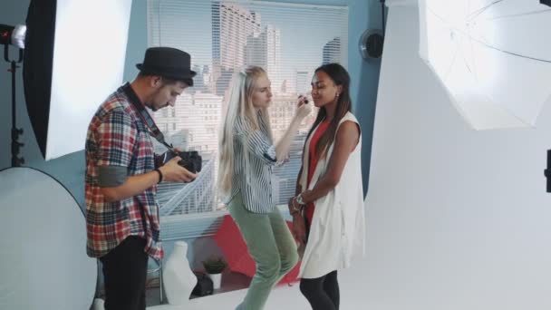 Foto de bastidores: maquiador aplicando maquiagem em modelo atraente de etnia africana . — Vídeo de Stock