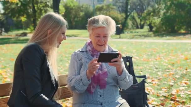 Az idősebb nagymama okostelefonon mutatja be az unokája fotóit — Stock videók