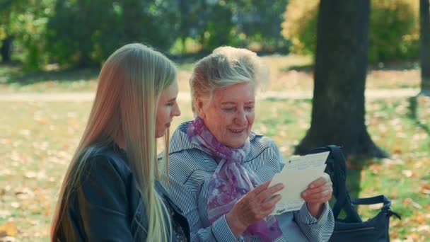 Primer plano medio de una anciana leyendo una carta a una joven bonita en el parque — Vídeo de stock