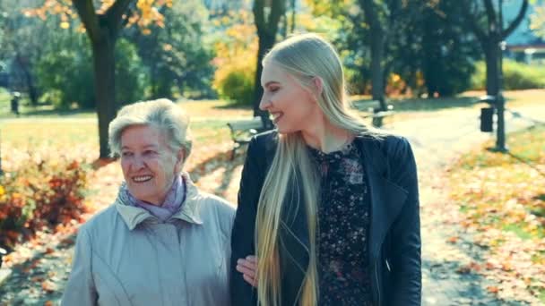 Vecchia e bella giovane donna che si abbracciano mentre camminano insieme nel parco — Video Stock