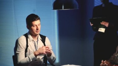 Polis dedektifinin sorgu odasındaki delilleri masaya attığı ortanca yakın plan.