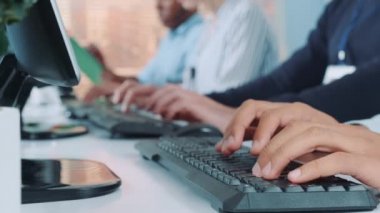 Close-up shot of operators hands typing on keyboard in modern office