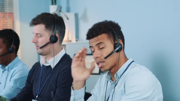 Střední záběr nespokojený multietnický agent call centra mluvit s klientem po telefonu — Stock video