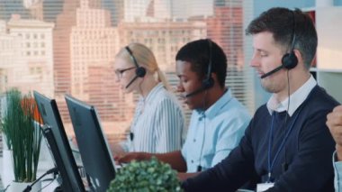 Caucasian customer support agent receiving an important document from his colleague while talking with client