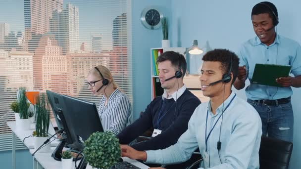 Multiethnic customer service representative telling his colleagues a joke while calling to the clients — Stock Video